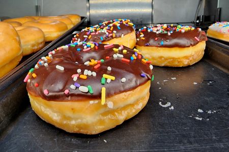 Chocolate iced ring donuts with sprinkles.