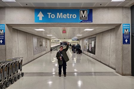Elyse points at a sign reading "To Metro" at Dulles Airport.