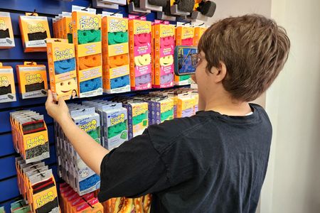 Elyse photographs a rack of Scrub Daddy sponges.