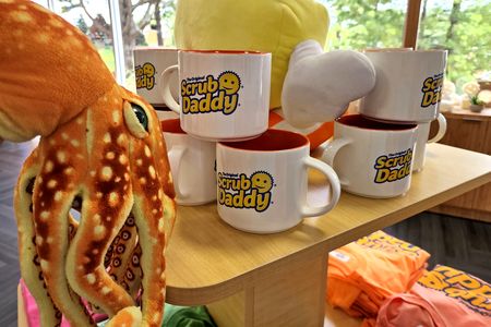 Woomy checks out the stack of Scrub Daddy mugs.