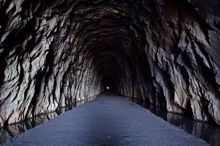 Interior of the tunnel.  The west portal is visible in the distance.  Note the bare rock.  Closer to the west portal, the tunnel was lined with brick, but it was bare rock nearer to the east portal.