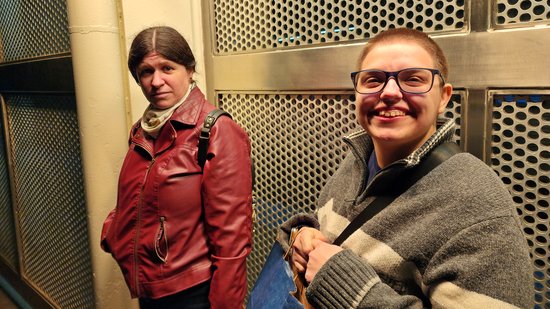 Elyse thoroughly enjoys the heat lamps at Howard station, while Sis looks on.