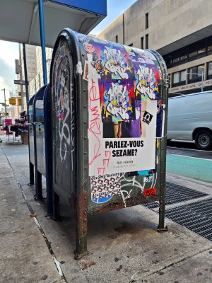 Mailbox covered in stickers and graffiti along 7th Avenue.