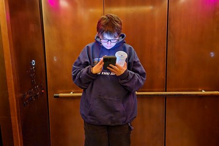 Elyse looks on her phone while we ride the elevator at Starbucks Reserve after going down to the restroom.