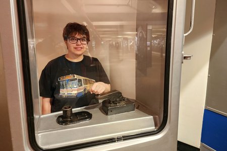 Elyse stands at the master controller of an R46 train.