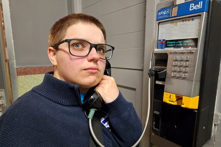 Elyse makes a face as she discovers a payphone in the entrance to the bowling alley, and that it actually works.