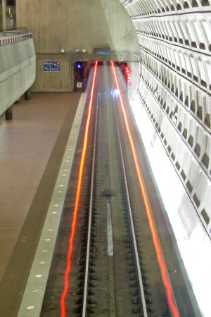 A Blue Line train departs Rosslyn on the outbound track.  At 21 years of age, I found it curious that the red streaks from the taillights were not straight.  I know now that the train does bounce side to side a little bit as it moves, which accounts for the wiggly lines.