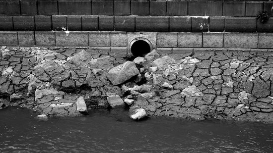 Dried and cracked mud in the canal due to lower water levels to support construction.