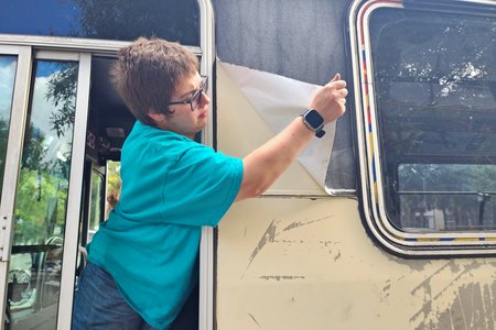 Elyse peels the wrap off of a panel behind the driver's window.