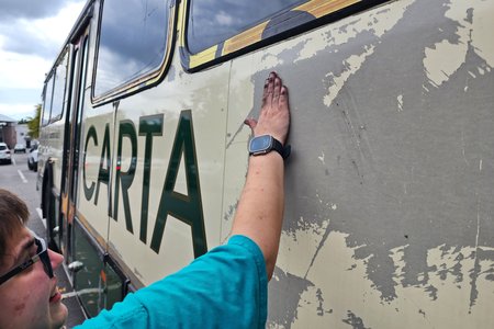 Elyse tries to work off some of the adhesive residue on the right side of the bus after we removed the vinyl.