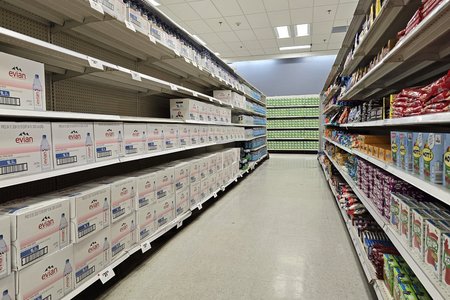 The left side of this aisle in the grocery section, containing Evian bottled water, was the only part of the store where product was stacked across a wide area one-deep to make a section appear full.