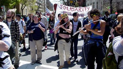 A group plays flutes while marching, providing a different style of music. They can he heard in the above movie clip.