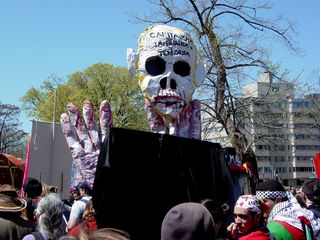 The George W. Bush/skull street puppet rises high above the crowd.