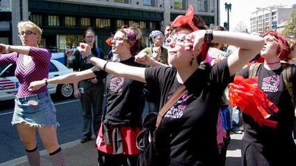 A group of radical cheerleaders does a cheer in the street at Dupont Circle.