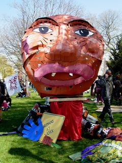 The largest of the street puppets by far, wheeled near the front of the march, made it in one piece. Other props used in the march lay on the ground around it.