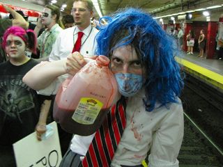 Blue Wig Girl, having made herself sufficiently bloody, holds up a milk jug containing more fake blood.