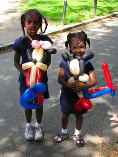 Two very adorable children with really awesome face paint, holding what are most likely the most complex balloon animals that I've ever seen.