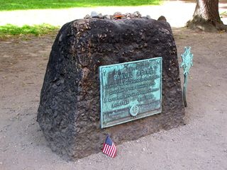 The headstone for Samuel Adams, and the stones and coins placed atop it.