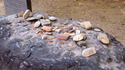 The headstone for Samuel Adams, and the stones and coins placed atop it.