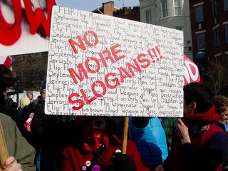 In the march, I soon met a woman wearing all red and a red bandanna holding up a sign saying "NO MORE SLOGANS!!!" with various slogans we've all heard penned in behind it. The slogans that the poster decries over and over again are "Flip Flop", "Bring It On", "Girly Men", "The Governator", "Mushroom Cloud", "Weapons Of Mass Destruction", "Git Saddam", "September The Eleventh", "Support Our Troops", "Evil Doers", and "Terrorists".