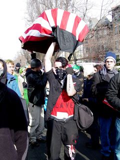 A man carrying a flag-draped coffin shows off a tattoo on his forearm, which reads, "INFIDEL".