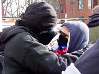 Two black bloc demonstrators share an intimate moment along the march route while we were stopped briefly.