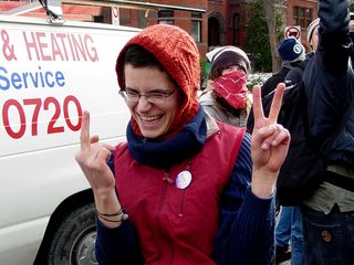 This woman shows off two trains of thought with her hands. On one hand, she gives George W. Bush the one-finger salute. And on the other hand, a peace sign.