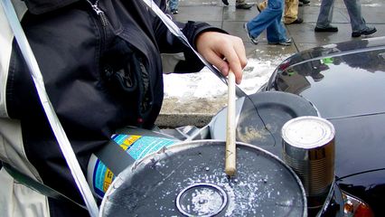 A person carrying a set of makeshift drums makes a beat for the marchers.