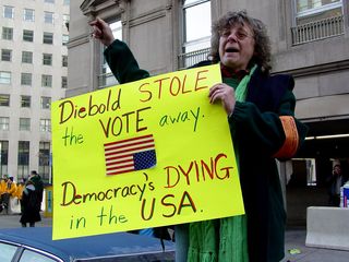 This woman, standing on her car, shows a poster criticizing Diebold, a manufacturer of election equipment.