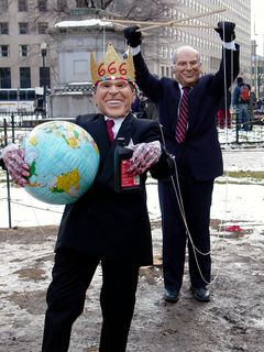 In another instance, two people dressed like George W. Bush and Dick Cheney. The man in the Bush mask wore a gold crown saying "666", held an inflatable globe and a bottle of motor oil, and had strings attached to his arms. The strings were to make Bush look like a puppet, and they were held by another man wearing a Dick Cheney mask.