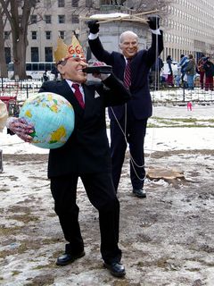 In another instance, two people dressed like George W. Bush and Dick Cheney. The man in the Bush mask wore a gold crown saying "666", held an inflatable globe and a bottle of motor oil, and had strings attached to his arms. The strings were to make Bush look like a puppet, and they were held by another man wearing a Dick Cheney mask.
