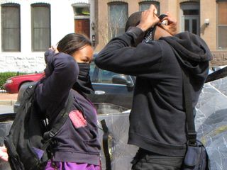 Two demonstrators readjust their masks before continuing.