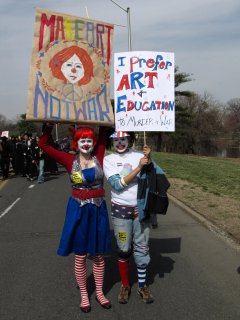 Two women dressed in clown makeup, advocating art and education over war.