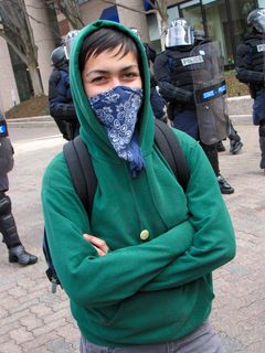 A masked demonstrator poses for a photo in front of the cops.