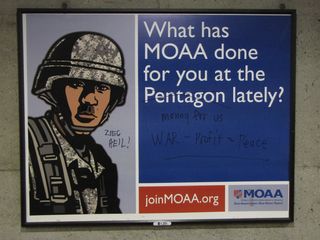 Metro advertisement for the Military Officers Association of America at Crystal City station, after anti-war protesters had their way with it.