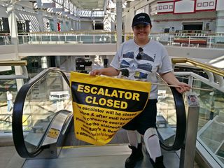 Elyse poses for a photo with the "Escalator Closed" sign.