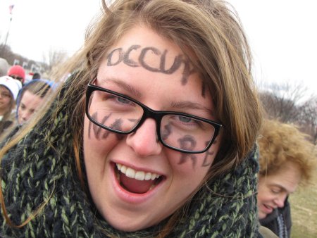 A woman appears with "OCCUPY NATURE" written on her face at the Forward On Climate rally in Washington DC.