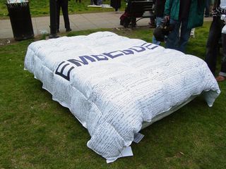 A mattress covered with a "blanket of lies" carries the phrase "EMBEDDED" In large, bold letters.