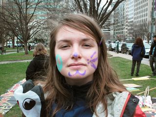 Face painting, with a peace sign on one side, and catlike features on the other.
