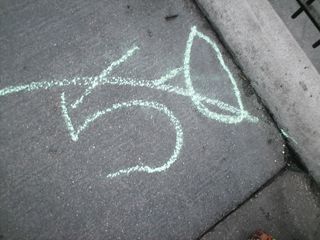 A chalked message on the sidewalk gives an anti-police message with a slash through "5-0".