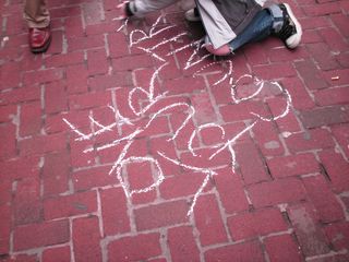 A demonstrator writes "Love your country" on the sidewalk in chalk. I personally think that this sends an important message. We don't hate America by any means. In fact, by coming out to protest, we are showing that we love the country more than most, but believe it's going in the wrong direction, and that it indeed can be improved. After all, it's not "my country, right or wrong". It's "my country" when it's right, and when it's wrong, I make it right.