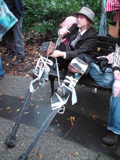 A woman straps on a set of stilts. A group of people would walk on stilts the entire way from Murrow Park to Luther Place.