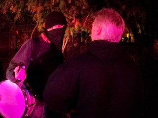 A police officer hassles a black bloc participant. This photo was taken just before the officer forcibly yanked the demonstrator's mask down.