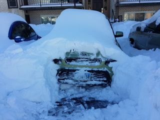Clearing the snow from the front of the car, but still firmly stuck in place, as the wheels aren't free yet.