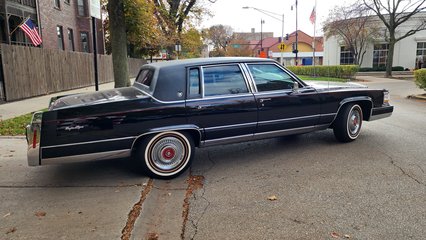 A Cadillac Brougham D'Elegance comes out of the alley from the opposite side of Oakley Avenue.