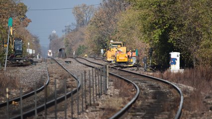 A crew works on a maintenance vehicle while our train approaches in the distance.