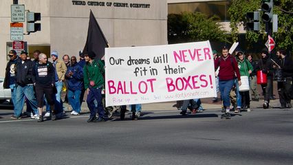 Participants in the feeder march wait to cross the street at the opposite corner of 16th and Eye Streets, and then held up their "Our dreams will never fit in their ballot boxes" banner for all to see while crossing.