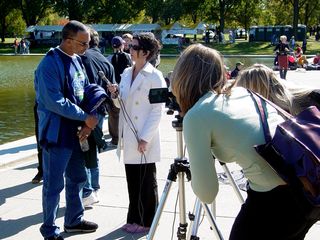 Near the reflecting pool, a woman conducts an interview.