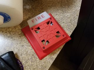 Unscrewing the fire alarm from the wall, leaving only the anchors in place.