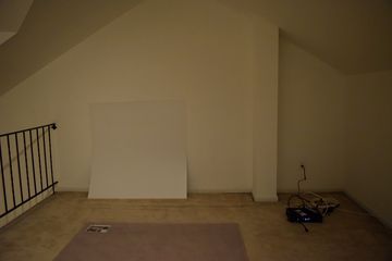 A near-empty mezzanine, with only a chair mat, a cable box, and a future wallhanging in the room.